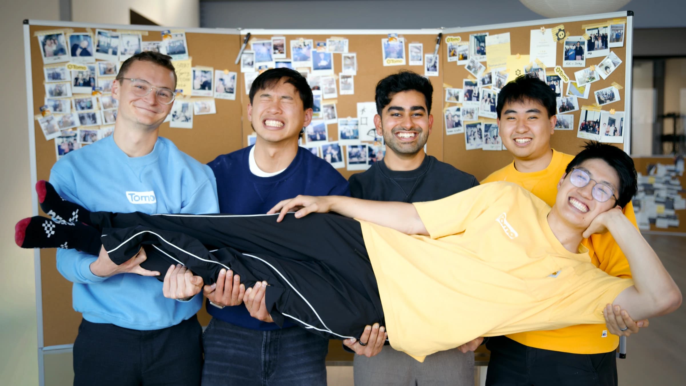 Team posing by the office corkboard